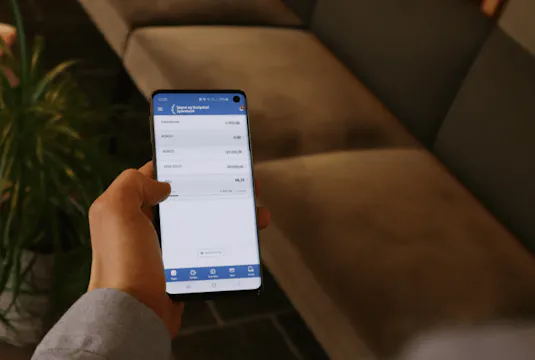Hånd som holder en mobil. Personen er innlogget i mobilbanken.