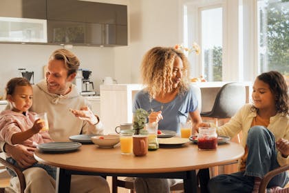 Familie smilende rundt frokostbordet.