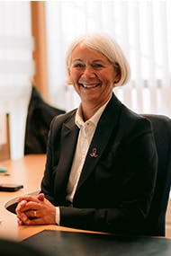 Forsikringsrådgiver sitter smilende på kontoret sitt.